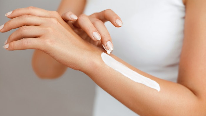 Woman applying lotion to arm