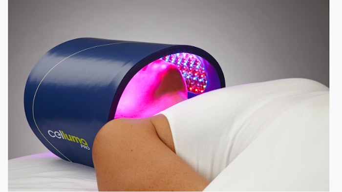 Woman in bed using Celluma light therapy device across her face