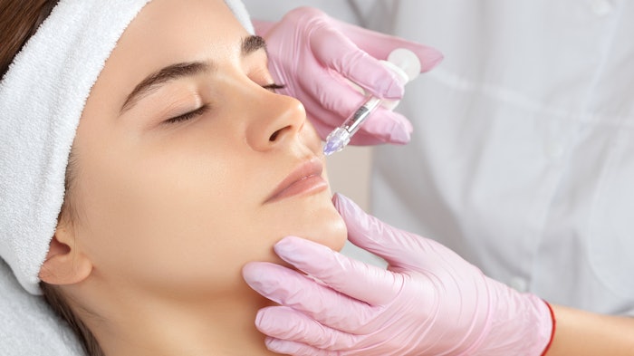 Women receiving hyaluronic acid filler injections to the lip.