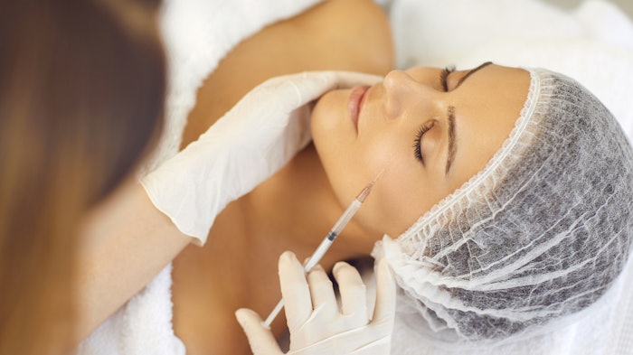 Woman getting a dermal filler injection in the cheek area.