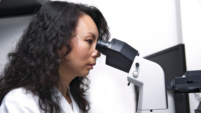 female scientist observing micro-organisms through microscope