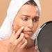 Woman checking her acne in mirror