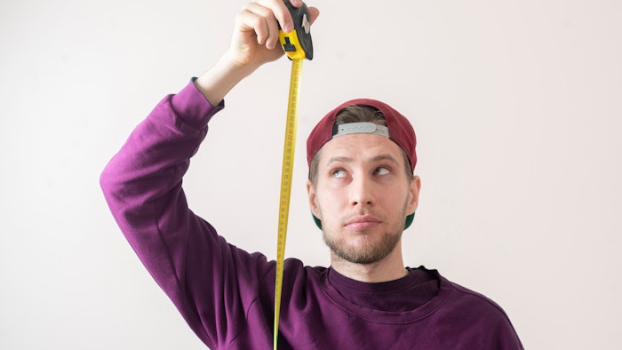 simple adult teenager male person with a roll tape measure the height against the wall