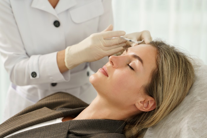 Woman during facial filler injections in aesthetic medical clinic