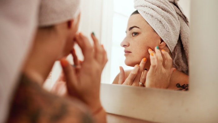 Beauty, acne and woman cleaning her face for skincare morning routine in her bathroom in a home or house