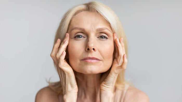 Antiage skincare. Senior woman touching skin near eyes and looking at camera