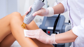 Close-up of a female cosmetologist in a medical coat making a young woman a procedure laser hair removal for leg