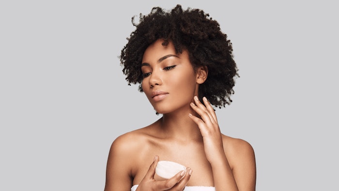 Black woman applying skincare product