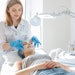 Woman professional doctor beautician applies a mask on a patient's face for skin care