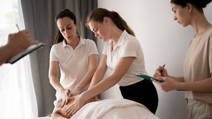 Woman teacher helping students become a masseuse, wellness massage training
