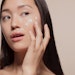 Asian woman applying moisturizer to her face