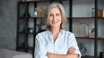 Smiling confident stylish mature middle aged woman standing at home office.