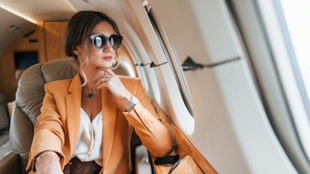 In sunglasses. Young passenger woman in yellow clothes is flying in the plane