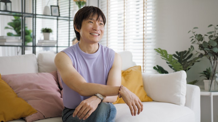 Gay queer asian man non-binary influencer sitting easy at home sofa. Asia non binary LGBT young guy adult two people happy relax