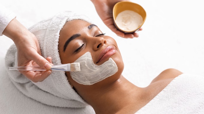 Top view of beauty therapist applying face mask