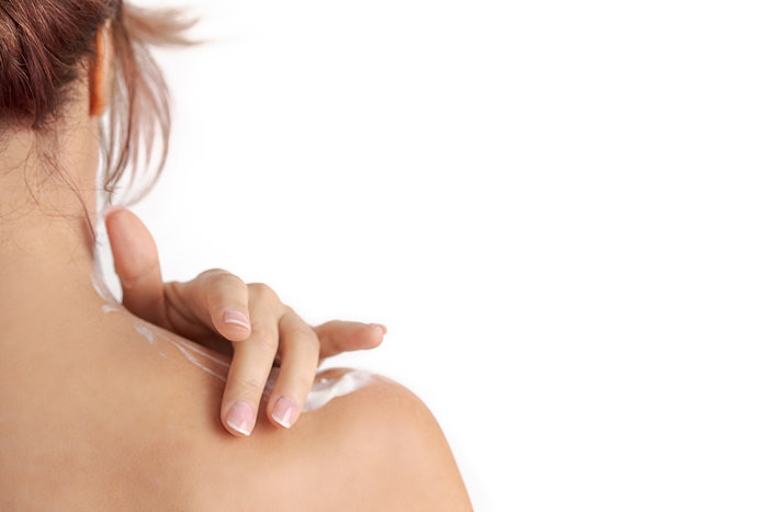 red hair woman's hand applying cream on her shoulder. Concept of smooth skin, skincare, cosmetics, wellness center, healthy lifestyle
