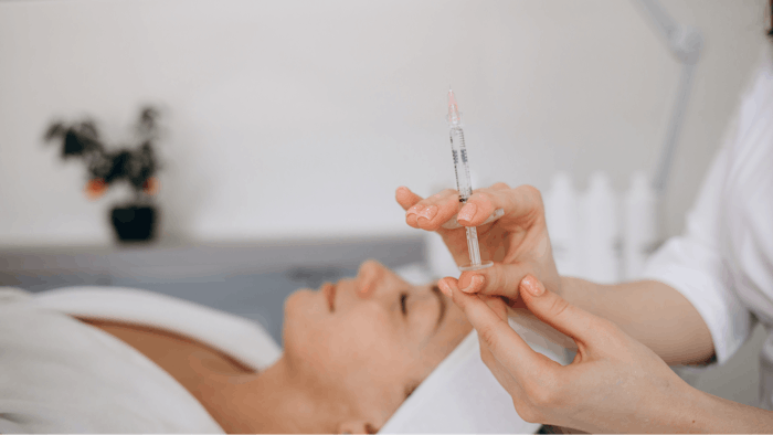Beautiful woman gets botox injection in her face. Adult girl gets cosmetic injection of botox in a clinic.