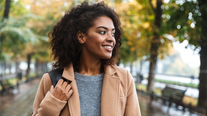 Beautiful young african woman wearing coat walking outdoors