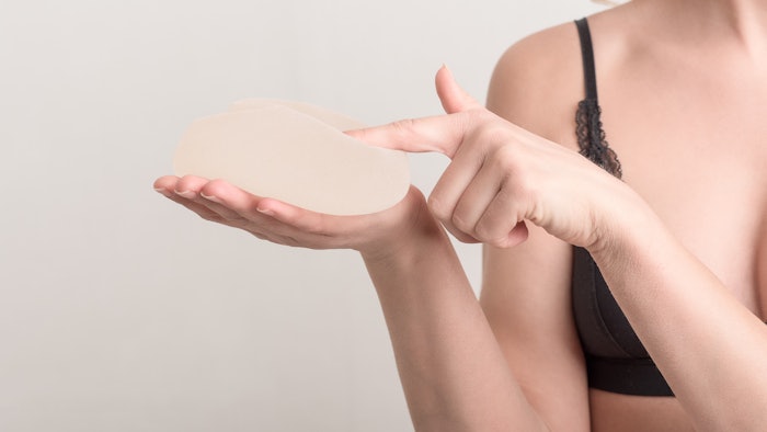 Young woman touching her breast implant before surgery.