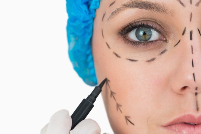 Plastic surgeon marking woman's face