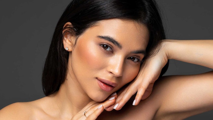 beautiful brunette posing hands under chin slightly smiling