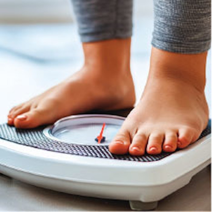 Photo of person's feet standing on a scale to measure weight and weight loss.