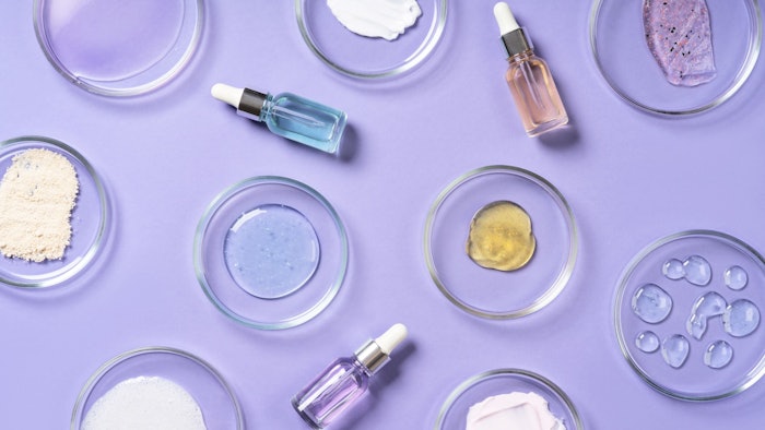 Cosmetic products, scrub, face serum and gel in many petri dishes on a violet background. Cosmetics laboratory research concept.