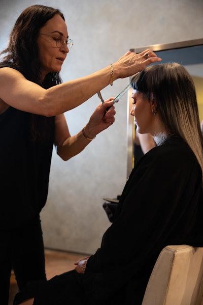 Marylle Koken places a comb in a client's bangs as she styles them.