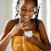 Beautiful Black Woman In Orange Towel Dipping Finger Into White Face Cream Jar Adobe Stock 578686567 (1)
