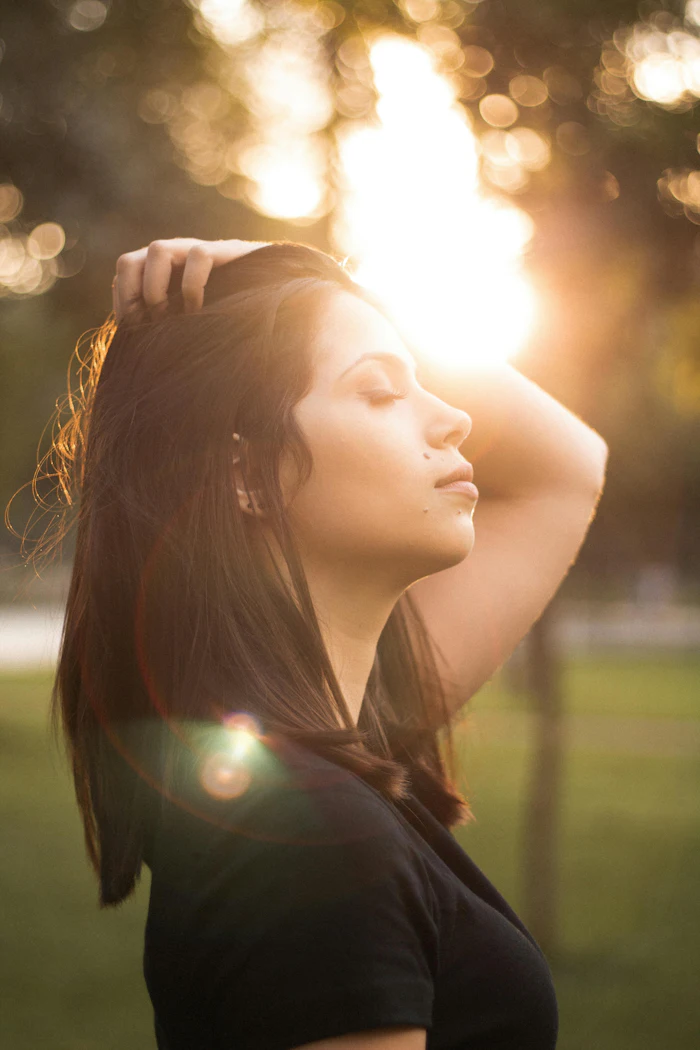 Person with long hair tilting head back, bathed in warm sunset light