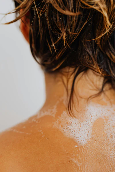 Wet hair and shoulders with soft soap bubbles in warm, golden light