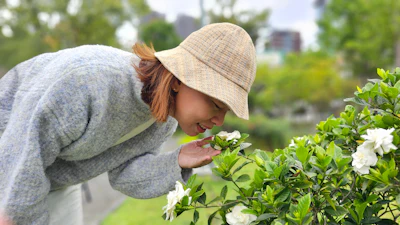 Woman in straw hat smelling white flowers in a lush garden