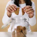 Woman breaking a cookie in half above a glass jar filled with homemade cookies