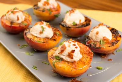 Roasted apricot halves topped with sour cream and crispy bacon bits on a gray plate