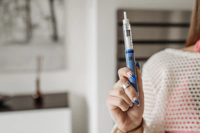 Person holding a blue insulin pen with needle for diabetes medication injection