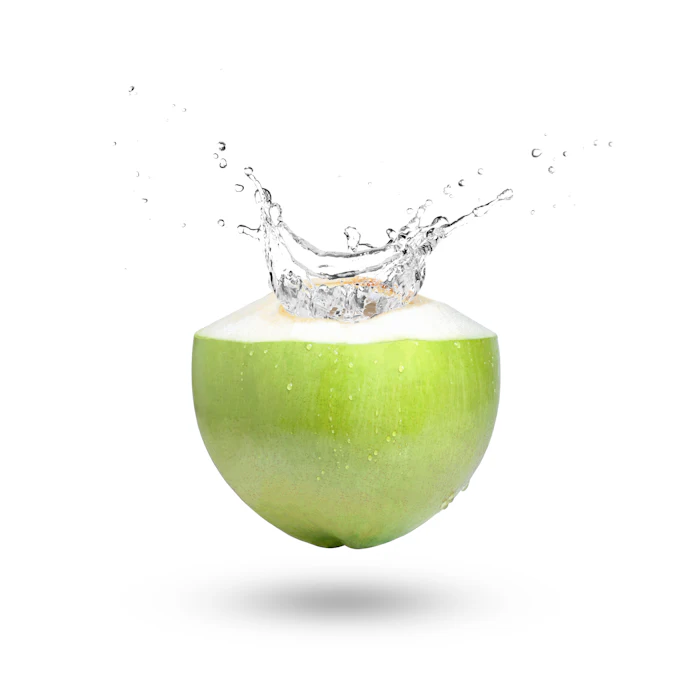 Fresh green coconut with water splash erupting from the top against white background