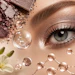 Close-up of eye makeup with crushed eyeshadow powder, water droplets, and white flowers in a beauty product composition