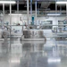 Industrial manufacturing facility with stainless steel tanks and blue processing equipment in a modern factory setting