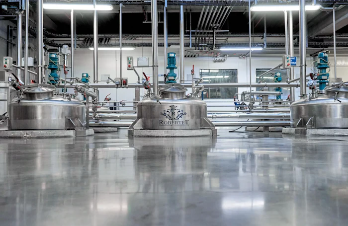Industrial manufacturing facility with stainless steel tanks and blue processing equipment in a modern factory setting