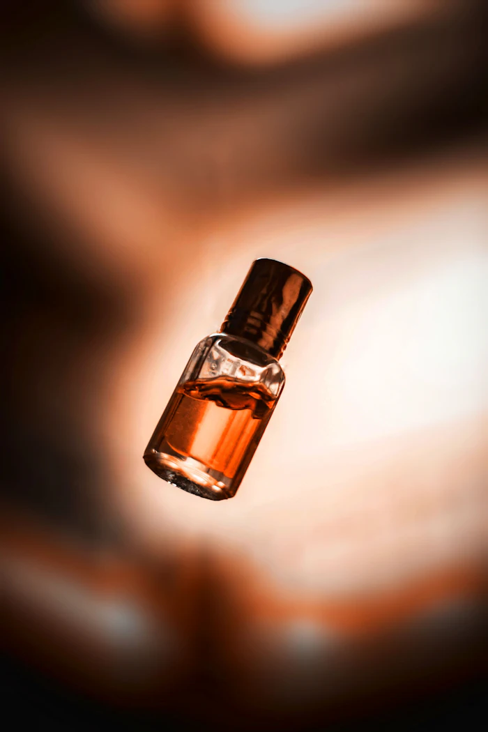 Golden amber fragrance bottle with dark cap against warm, blurred background