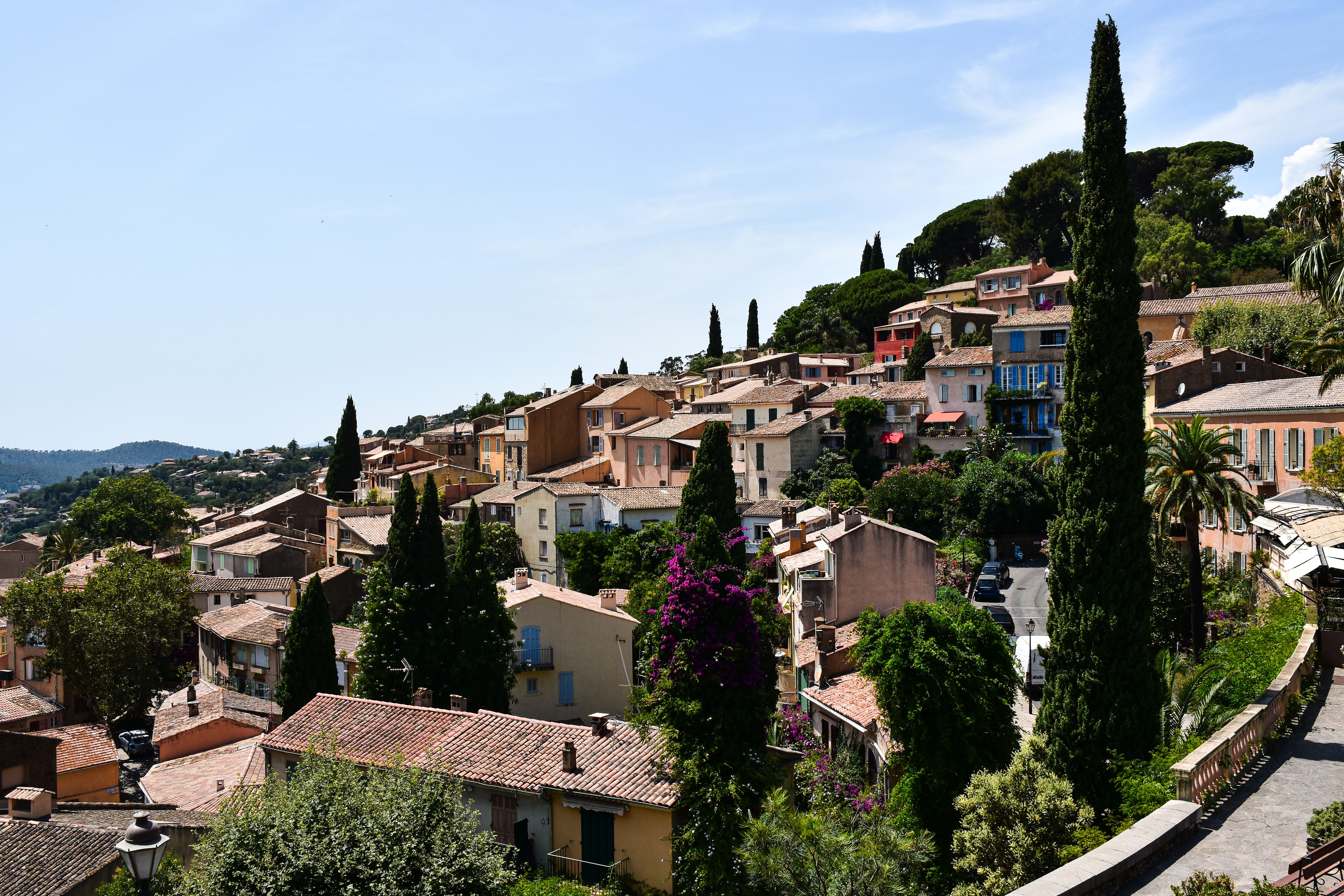 Hillside Mediterranean village with terracotta buildings, cypress trees, and colorful facades overlooking coastal landscape