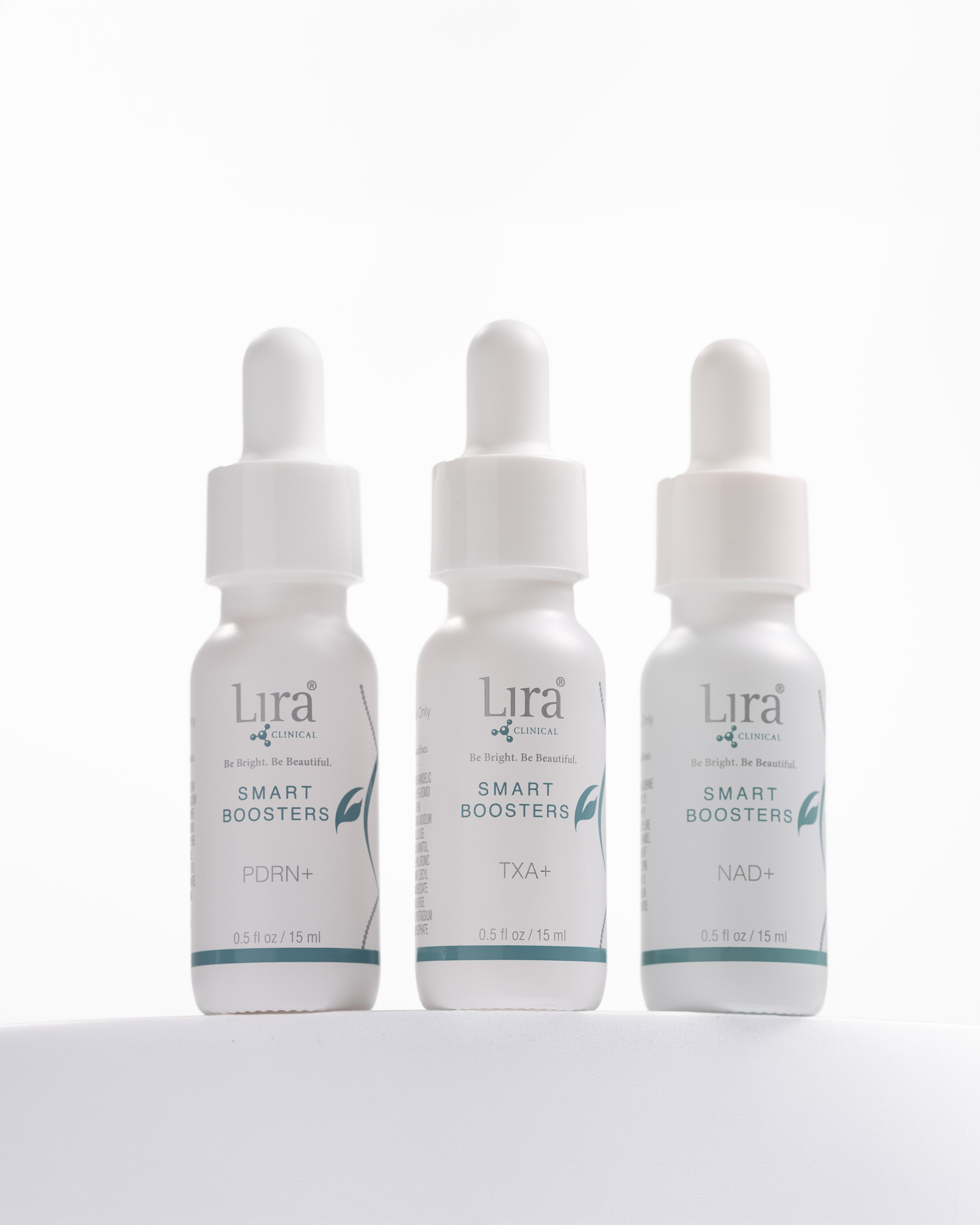 Three white dropper bottles of Lira Clinical Smart Boosters serums with teal accents, labeled PDRN+, TXA+, and NAD+