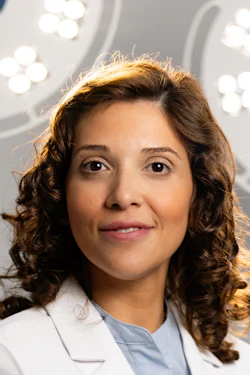 Female cosmetic surgeon in white lab coat at South Florida Center for Cosmetic Surgery, standing in front of surgical lights