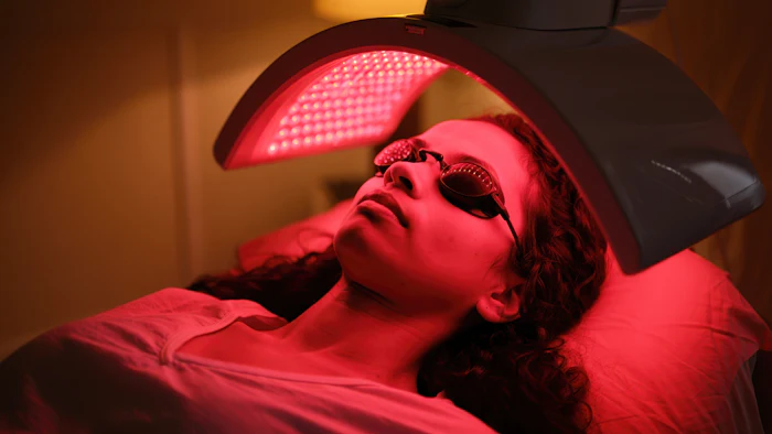 Person receiving red light therapy treatment under LED panel device