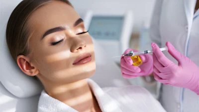 Woman receiving facial injection treatment from healthcare professional wearing pink gloves in medical clinic