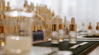 Collection of luxury cosmetic serum bottles with gold dropper caps displayed on black and white surfaces