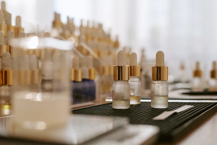 Collection of luxury cosmetic serum bottles with gold dropper caps displayed on black and white surfaces