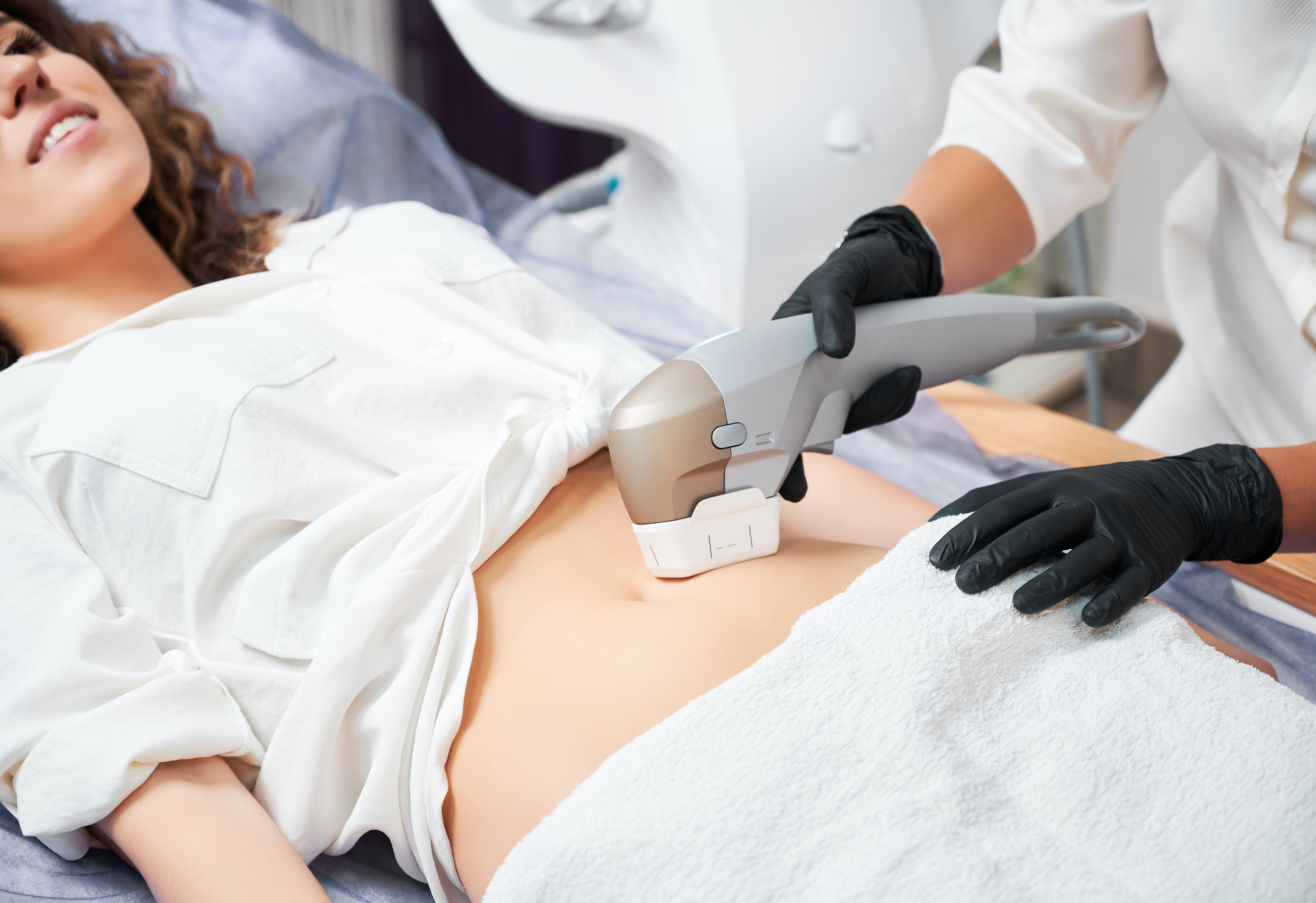Healthcare professional performing abdominal ultrasound examination on patient wearing white gown