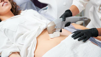 Healthcare professional performing abdominal ultrasound examination on patient wearing white gown
