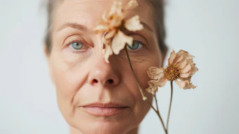 Woman's face with wilted flowers symbolizing aging and the passage of time